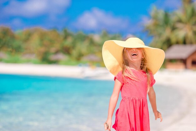 Adorable petite fille au chapeau à la plage pendant les vacances d'été