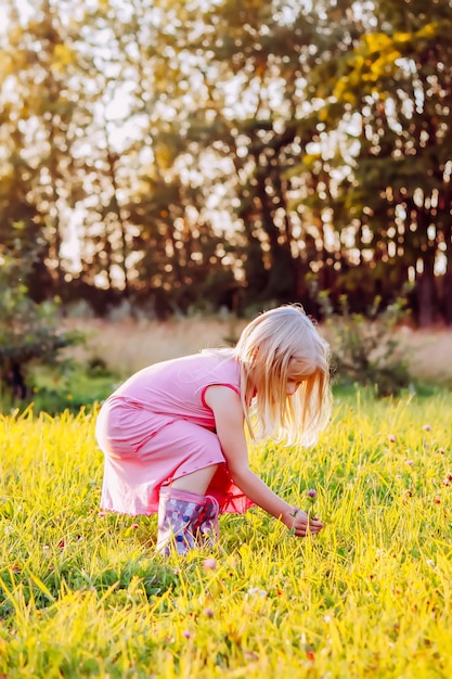 Adorable petite fille blonde dans un pré en journée d'été ensoleillée