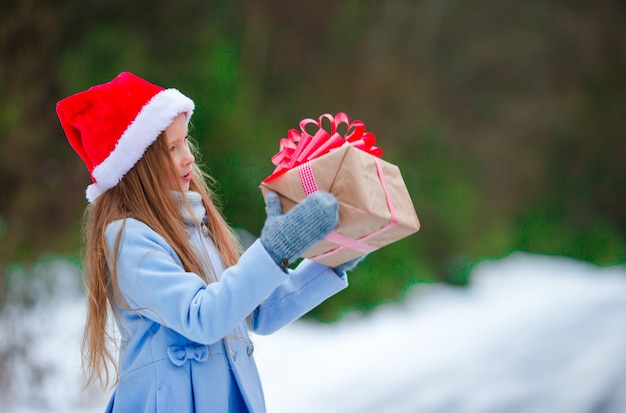 Adorable petite fille avec un cadeau de Noël en hiver