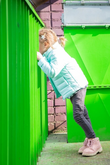 Adorable petite fille caucasienne assise sur l'escalier en fer avec intérêt en regardant les passants