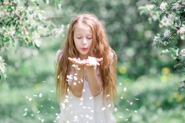 Adorable petite fille dans un jardin de pommiers en fleurs sur une belle journée de printemps