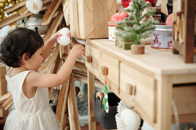 Adorable petite fille décorant la salle avec des jouets de noël pour la célébration