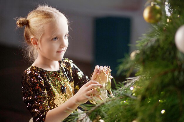 Adorable petite fille décorer un arbre de Noël à la maison. Célébration de Noël et du nouvel an.