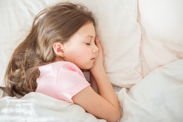 Adorable petite fille dort dans le lit