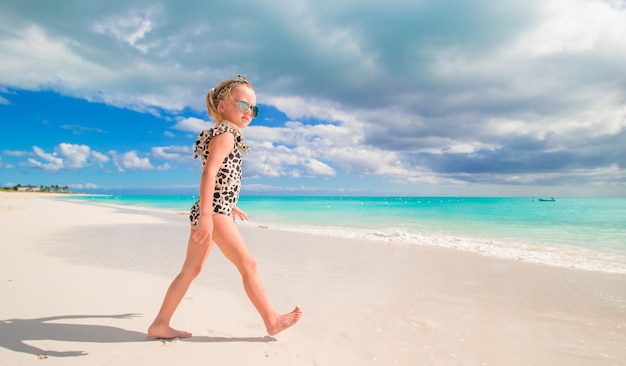 Adorable petite fille en eau peu profonde sur la plage