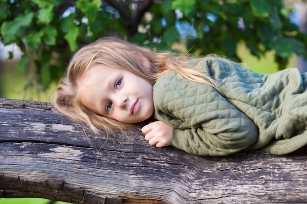 Adorable petite fille sur un grand arbre dans un magnifique parc en automne