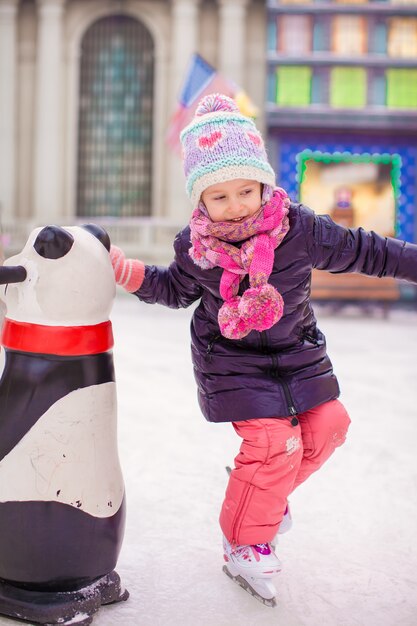 Adorable petite fille heureuse en train de patiner à la patinoire