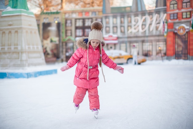 Adorable petite fille heureuse en train de patiner à la patinoire