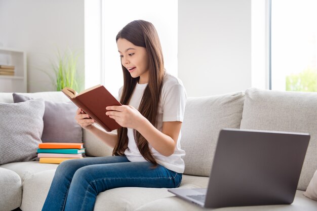 adorable petite fille intelligente curieuse lire un livre profitez de vous détendre à l'intérieur