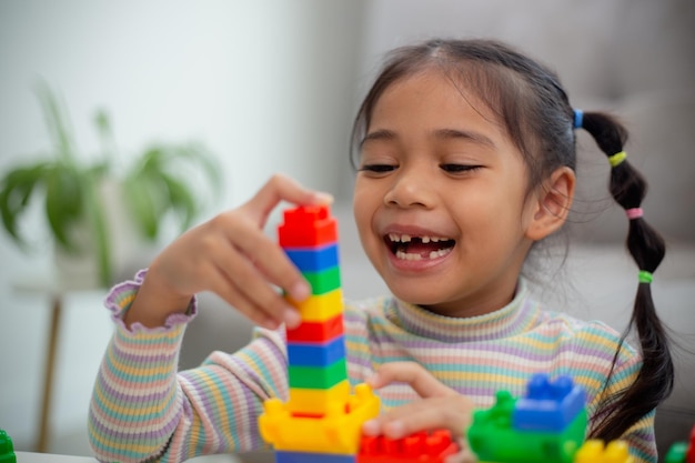 Une adorable petite fille jouant à des blocs de jouets dans une pièce lumineuse x9