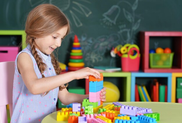 Adorable petite fille jouant avec des blocs de plastique colorés