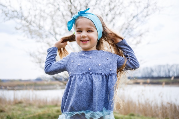 Adorable petite fille jouant dans un jardin de pommiers en fleurs à la chasse aux œufs de Pâques, courant et souriant. Enfant dans un verger de printemps avec des fleurs de cerisier.