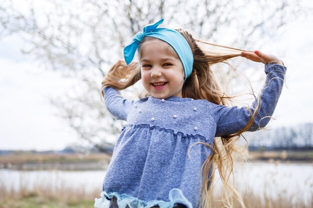 Adorable petite fille jouant dans un jardin de pommiers en fleurs à la chasse aux œufs de Pâques, courant et souriant. Enfant dans un verger de printemps avec des fleurs de cerisier.