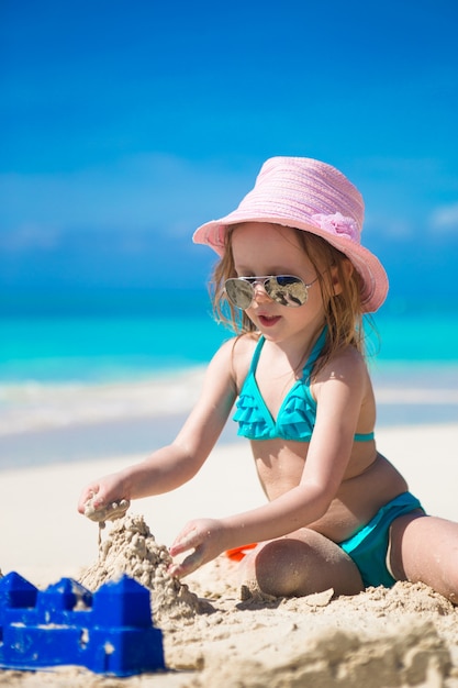 Adorable petite fille jouant avec du sable sur une plage tropicale parfaite