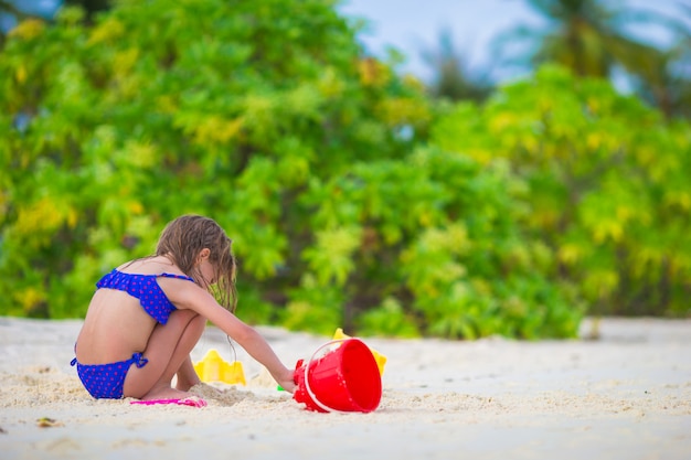 Adorable petite fille jouant avec des jouets de plage pendant des vacances tropicales