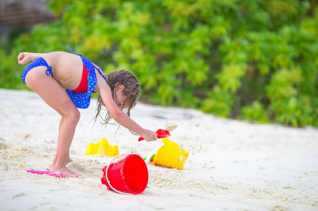 Adorable petite fille jouant avec des jouets de plage pendant des vacances tropicales