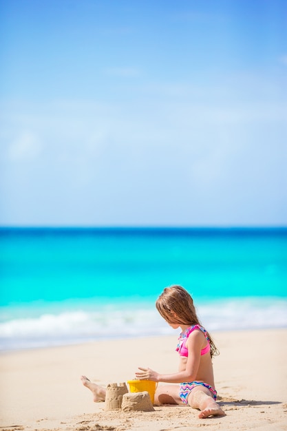Adorable petite fille jouant avec des jouets de plage sur la plage tropiale blanche