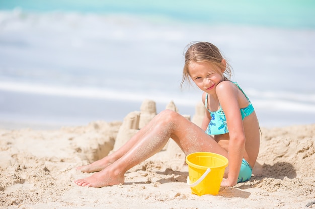 Adorable petite fille jouant avec des jouets de plage sur la plage tropiale blanche