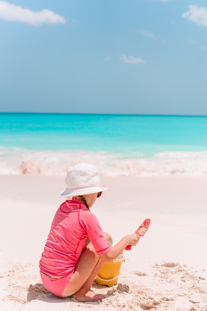 Adorable petite fille jouant avec des jouets de plage sur la plage tropicale blanche