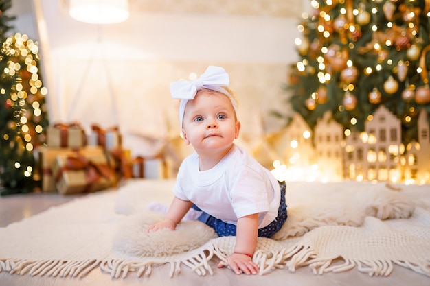 Adorable petite fille jouant avec des ornements sous un sapin de Noël décoré