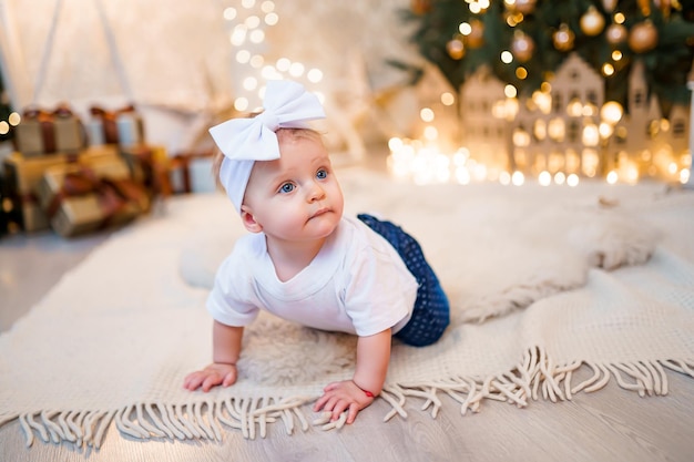 Adorable petite fille jouant avec des ornements sous un sapin de Noël décoré