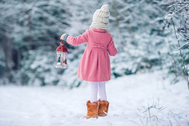 Adorable petite fille avec lampe de poche et bougie en hiver