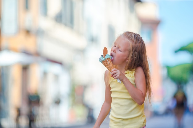 Adorable petite fille mangeant des glaces en plein air en été dans la ville
