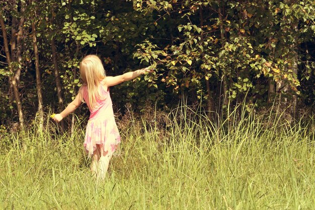 Adorable petite fille marchant dans le champ d'été à la campagne