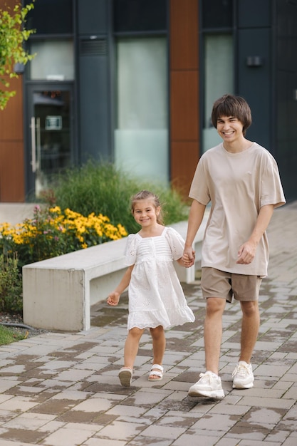 Adorable petite fille marchant dans le parc avec son frère adolescent Happy kids