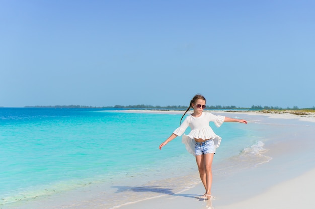 Adorable petite fille marchant le long de la plage de sable blanc des Caraïbes