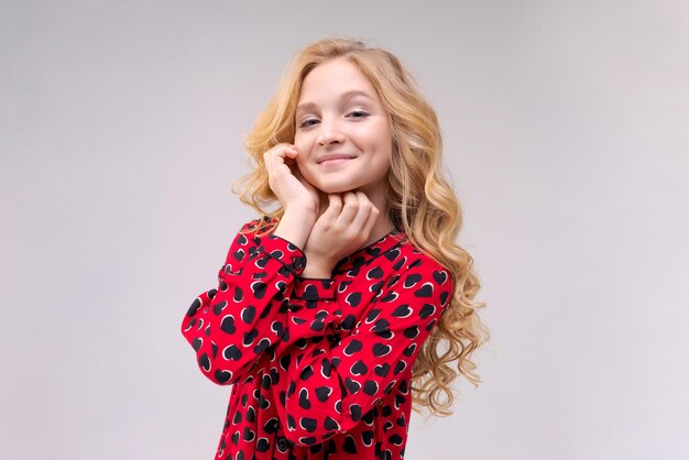 Adorable petite fille de mode hipster vêtue d'une robe rouge avec des coeurs blonds longs cheveux lâches ondulés...