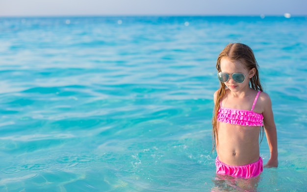 Adorable petite fille nage dans une eau turquoise