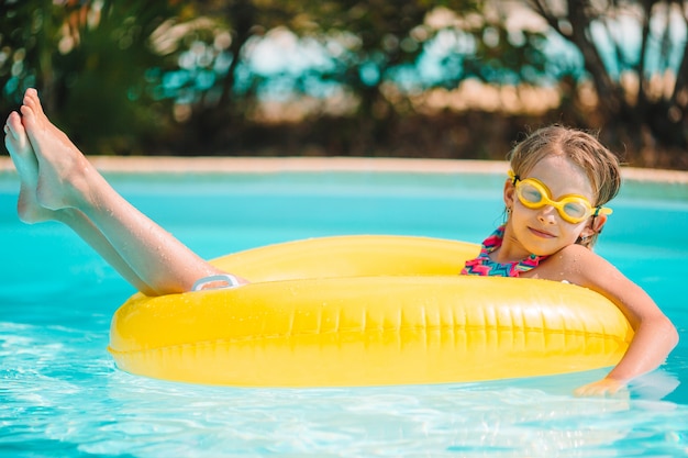 Adorable petite fille nageant dans la piscine extérieure