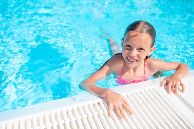 Adorable petite fille nageant dans la piscine extérieure