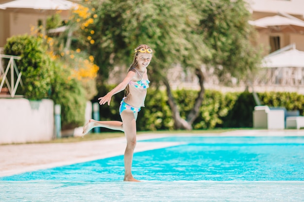 Adorable petite fille nageant dans la piscine extérieure