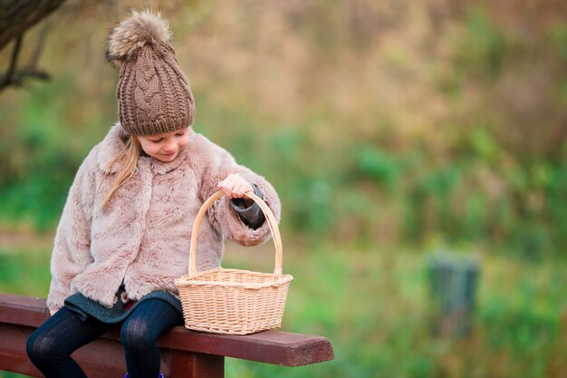 Adorable petite fille avec un panier en automne jour en plein air