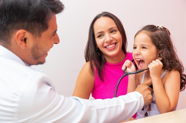 Adorable petite fille en pédiatrie jouant à l'écoute du coeur. L'enfant s'amuse à écouter sa prière avec le stéthoscope du médecin