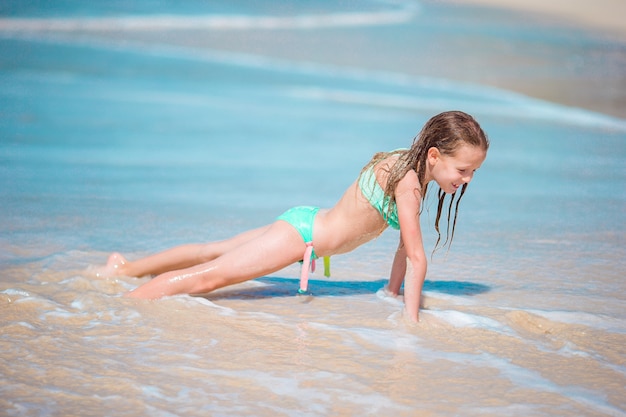 Adorable petite fille à la plage s'amuse dans l'eau peu profonde