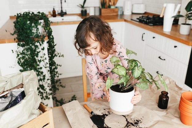 Adorable petite fille plante une plante d'intérieur en pot à la maison