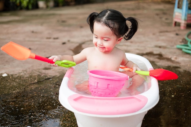 Adorable petite fille prenant un bain dans une baignoire blanche et jouant un jouet Vue de dessus d'un petit bébé mignon prenant un bain et une douche Enfant heureux dans la salle de bainImage de soins de santé jolie petite fille