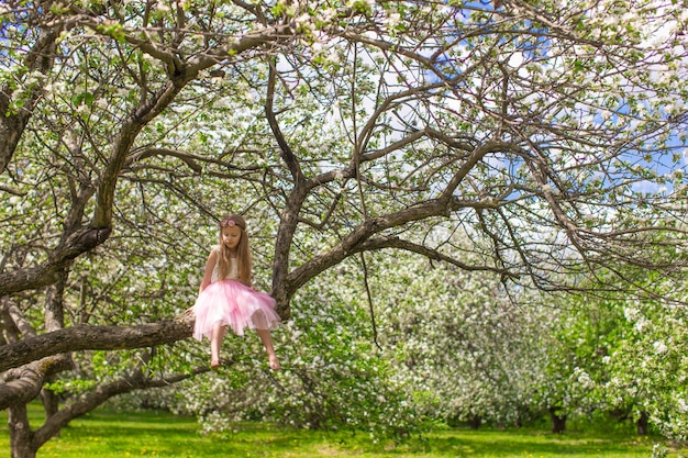 Photo adorable petite fille s'amuse dans un verger en fleurs