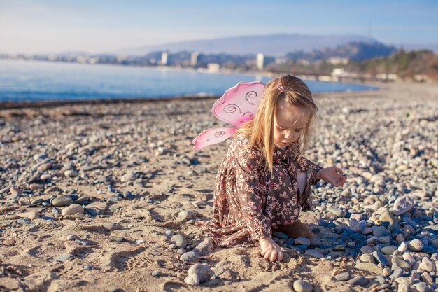 Adorable petite fille s'amuser sur la plage en une journée ensoleillée d'hiver