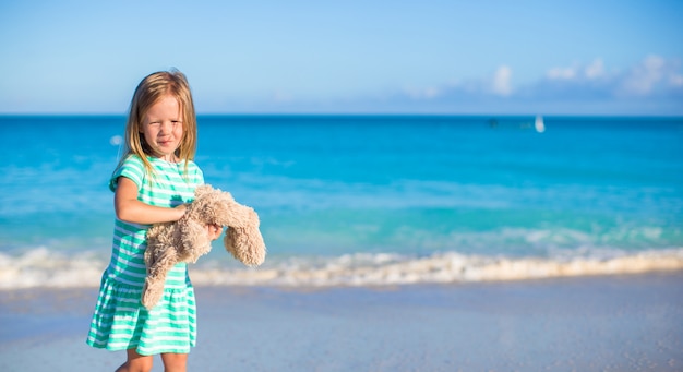 Adorable petite fille avec son jouet lapin en vacances de plage tropicale