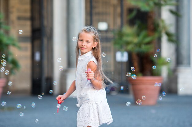 Adorable petite fille soufflant des bulles de savon dans le Trastevere à Rome, Italie