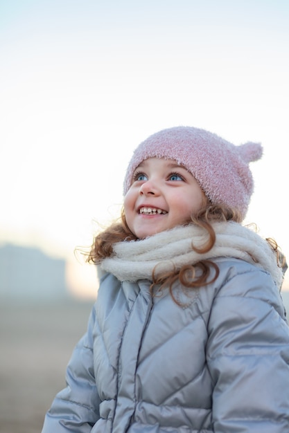 Adorable petite fille sourit et regarde le ciel.