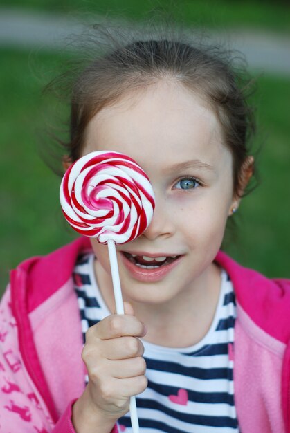 Adorable petite fille tenant une sucette tourbillonnante. S&#39;amuser.