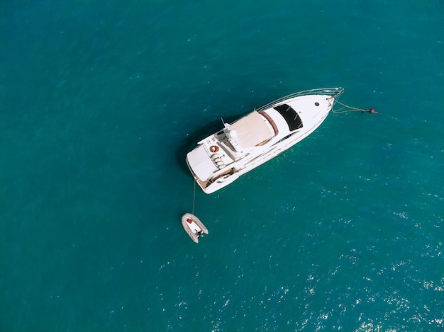 Adorable photo aérienne d'un immense yacht à deux étages et d'un petit bateau à côté naviguant sur la mer d'un bleu profond