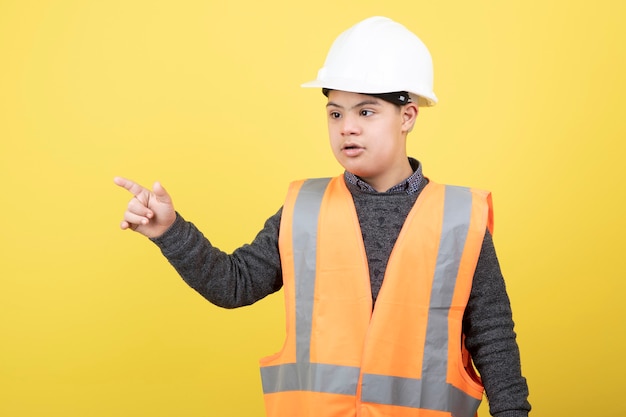 adorable travailleur de la construction en casque debout sur jaune.