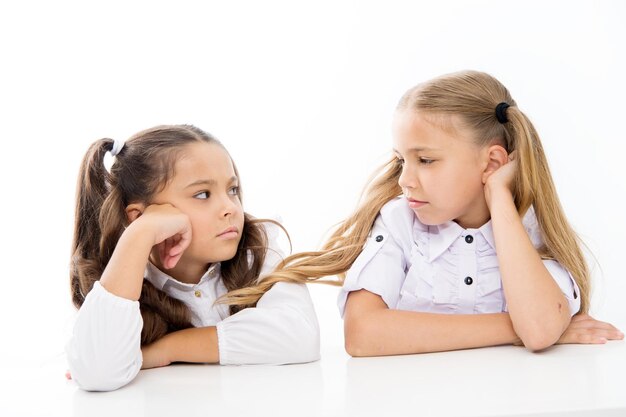 Adorables écolières Retour à l'école Concept d'éducation Belles filles meilleurs amis Style formel Enfance heureuse Écolières assis au bureau fond blanc Écolières amis émotionnels