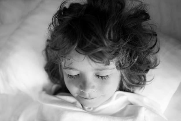 Adorables enfants dorment Enfant sur le lit de couchage heure du coucher heureuse dans la chambre blanche